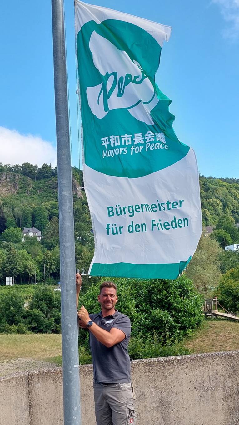 Ein Mann hisst die Mayors-for-Peace-Flagge in Gerolstein (Rheinland-Pfalz)